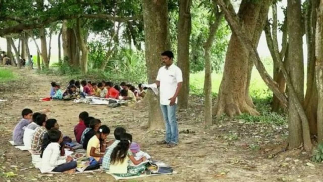 ಕಾರಟಗಿ: ನಿರ್ಮಾಣವಾಗದ ಕಟ್ಟಡ, ಮರದ ನೆರಳಿನಲ್ಲಿಯೇ ಮಕ್ಕಳಿಗೆ ಪಾಠ! ಕಾರಟಗಿ: ನಿರ್ಮಾಣವಾಗದ ಕಟ್ಟಡ, ಮರದ ನೆರಳಿನಲ್ಲಿಯೇ ಮಕ್ಕಳಿಗೆ ಪಾಠ!