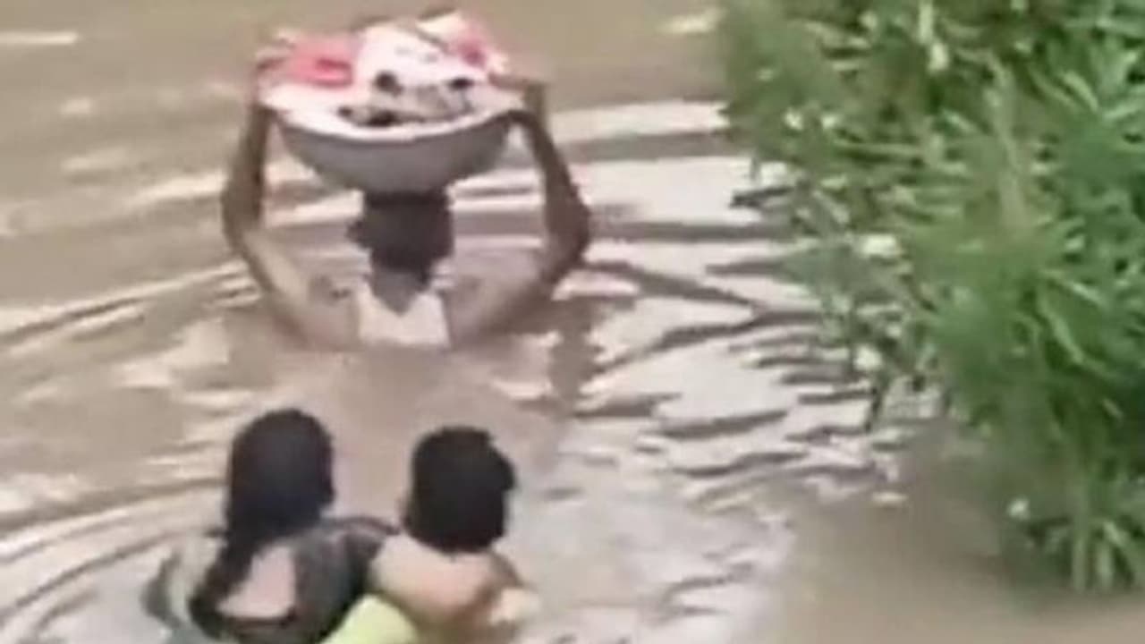 കനത്ത മഴ, വെള്ളപ്പൊക്കം, മാസങ്ങൾ മാത്രം പ്രായമുള്ള കുഞ്ഞിനെയും ചുമന്ന് കഴുത്തൊപ്പം വെള്ളത്തിലൊരാൾ
