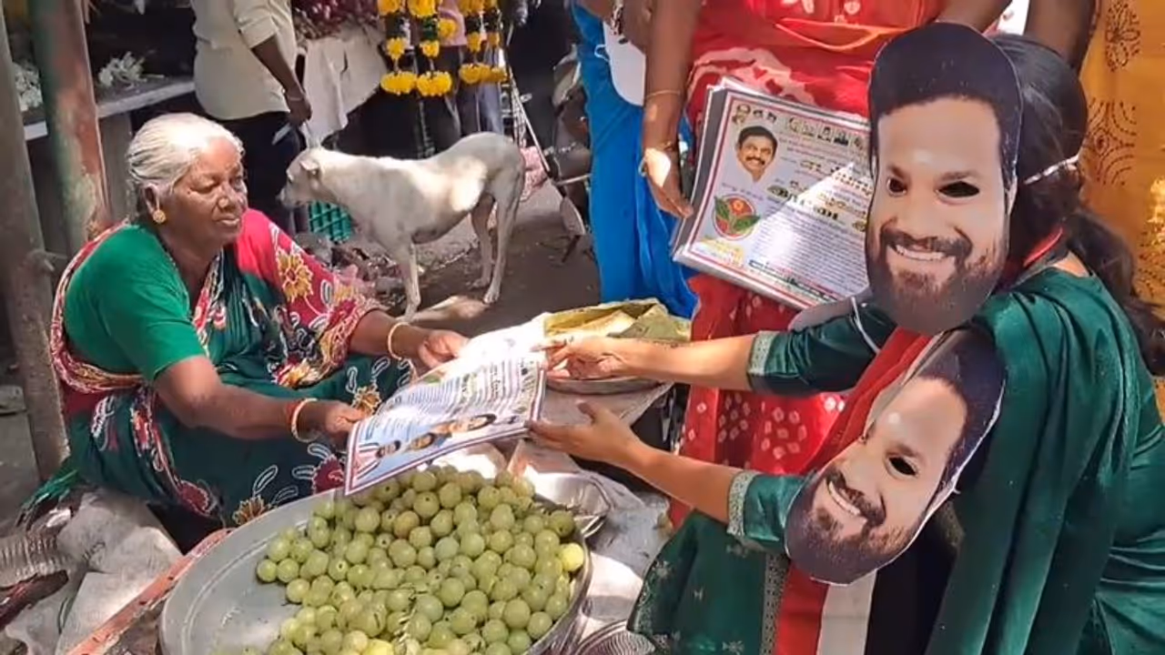 வேட்பாளரின் முகமூடியை அணிந்து கணவருக்காக வாக்கு சேகரித்த மனைவி; புதுவையில் விநோத பிரசாரம்