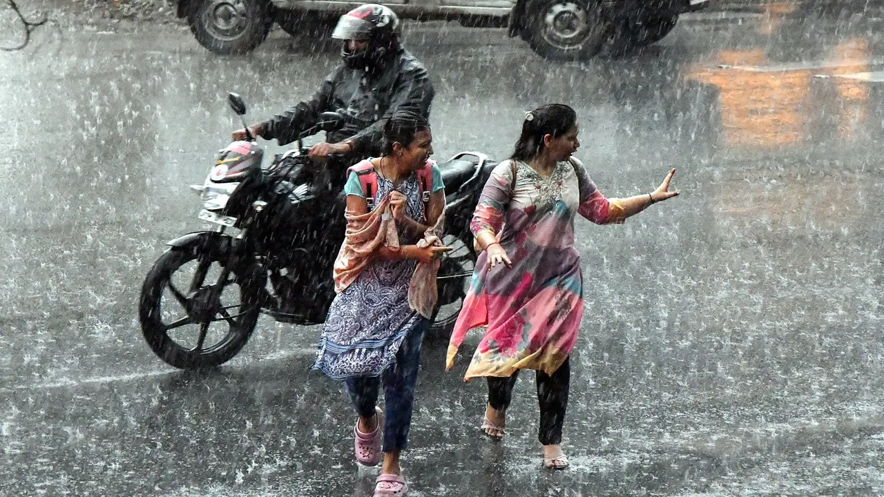 Women cross a road amid heavy rain