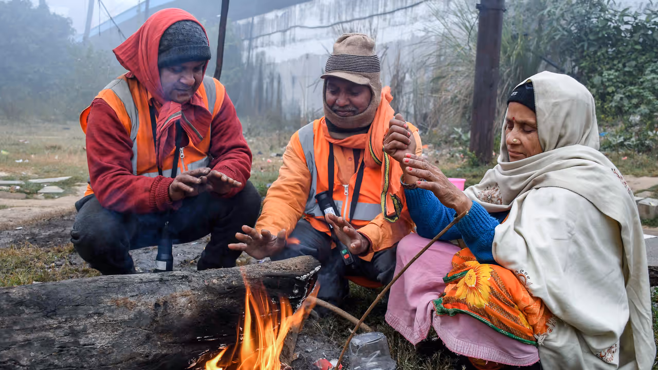 People warm themselves around a small bonfire on a winter morning People warm themselves around a small bonfire on a winter morning