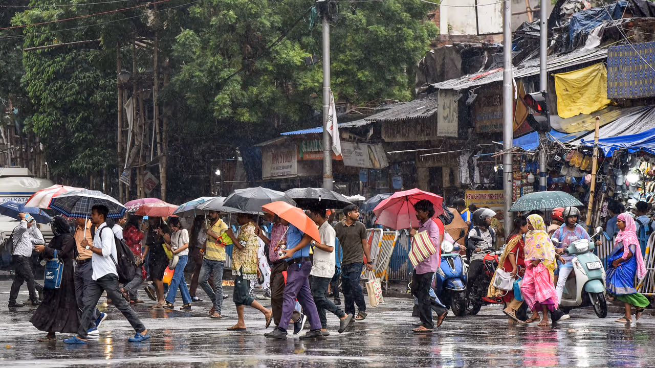 People carrying umbrellas cross the road amid heavy rain People carrying umbrellas cross the road amid heavy rain