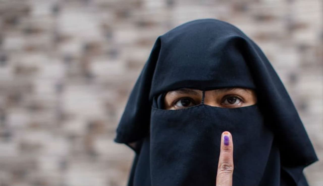 An Indian Muslim woman shows her indelible ink marked finger after casting her vote outside a polling station in Shaheen Bagh on February 8, 2020 in Delhi.