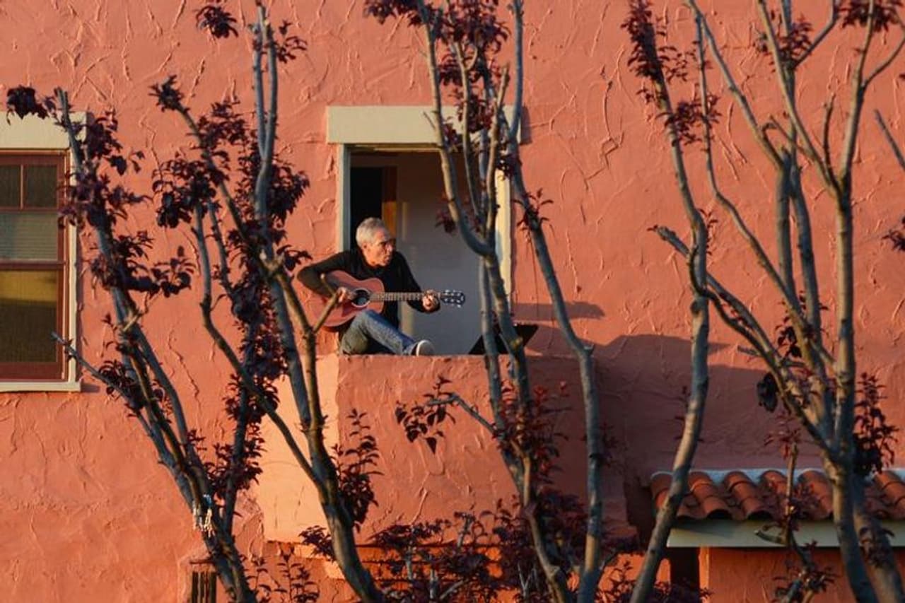 കാലിഫോർണിയ ഗവർണർ ഗാവിൻ ന്യൂസോം സംസ്ഥാന വ്യാപകമായി വീട്ടിലിരിക്കാന് നിര്ദ്ദേശിച്ചതിന് രണ്ട് ദിവസത്തിന് ശേഷം ഡാനി വർത്തൈമർ തന്റെ ബാൽക്കണിയിൽ നിന്ന് ഗിത്താർ വായിക്കുകയും അയൽവാസികൾക്കായി പാടുകയും ചെയ്യുന്നു. സംസ്ഥാനത്തെ 40 ദശലക്ഷം ആളുകളോടാണ് അവരുടെ വീടുകളിൽ താമസിക്കാൻ നിർദ്ദേശം നൽകിയത്. ഡാനിയെ പോലെ നമ്മുക്കും അയല്വാസികള്ക്ക് വേണ്ടി പാടാം. പക്ഷേ, നമ്മുടെ പാട്ട് മറ്റുള്ളവര്ക്ക് ശല്യമായി മാറാതിരിക്കാന് ശ്രദ്ധിക്കാം. കാലിഫോർണിയ ഗവർണർ ഗാവിൻ ന്യൂസോം സംസ്ഥാന വ്യാപകമായി വീട്ടിലിരിക്കാന് നിര്ദ്ദേശിച്ചതിന് രണ്ട് ദിവസത്തിന് ശേഷം ഡാനി വർത്തൈമർ തന്റെ ബാൽക്കണിയിൽ നിന്ന് ഗിത്താർ വായിക്കുകയും അയൽവാസികൾക്കായി പാടുകയും ചെയ്യുന്നു. സംസ്ഥാനത്തെ 40 ദശലക്ഷം ആളുകളോടാണ് അവരുടെ വീടുകളിൽ താമസിക്കാൻ നിർദ്ദേശം നൽകിയത്. ഡാനിയെ പോലെ നമ്മുക്കും അയല്വാസികള്ക്ക് വേണ്ടി പാടാം. പക്ഷേ, നമ്മുടെ പാട്ട് മറ്റുള്ളവര്ക്ക് ശല്യമായി മാറാതിരിക്കാന് ശ്രദ്ധിക്കാം.