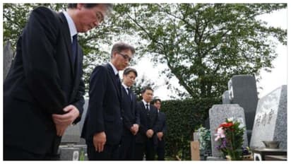 Japanese police officers bow their heads to the grave