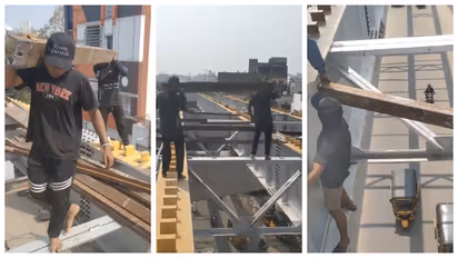 Workers Carry Heavy Iron Rods Over Busy Traffic