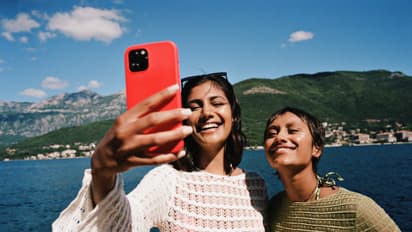 Woman taking selfie with female friend on smart phone
