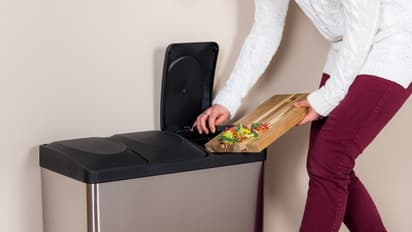 woman-throwing-wasted-food-into-steel-bin