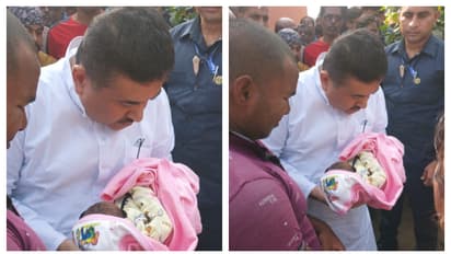BJP leader Suvendu Adhikari holds the newborn child of the victim of the saline incident bsm