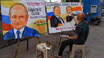A teacher from Gurukul school of art paints a poster welcoming Russian President Vladimir Putin to India outside their art school in Mumbai.