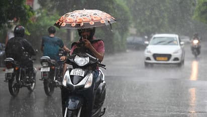 A commuter riding through rain in Delhi