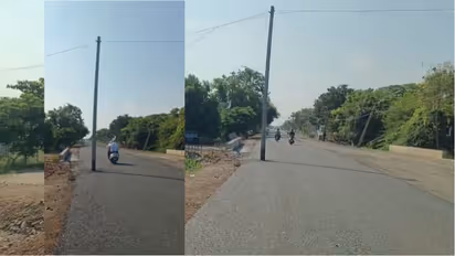 Electric pole stands in the middle of a newly tarred road in Ballari