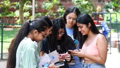 Students check their CBSE 12th board results on their mobile phones