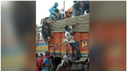 ഒരു കൈയിൽ കുഞ്ഞ്, മറുകൈ കൊണ്ട് ട്രക്കിൽ തൂങ്ങിക്കയറി... ഉള്ളുലയ്ക്കുന്ന ഈ ഫോട്ടോയ്ക്ക് പിന്നിലൊരു കഥയുണ്ട്...