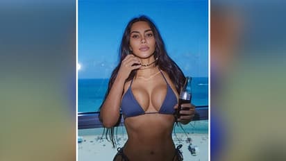 Kim Kardashian wishes Happy Birthday to Kourtney Kardashian wearing blue swimwear
