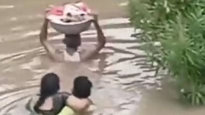 കനത്ത മഴ, വെള്ളപ്പൊക്കം, മാസങ്ങൾ മാത്രം പ്രായമുള്ള കുഞ്ഞിനെയും ചുമന്ന് കഴുത്തൊപ്പം വെള്ളത്തിലൊരാൾ