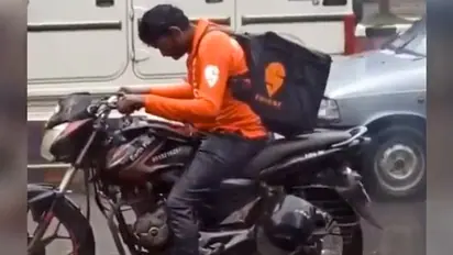 Watch: Swiggy delivery agent waits helplessly in heavy rain at traffic signal; wins netizens' heart