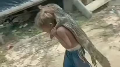 മുതലക്കുഞ്ഞിനേയും ചുമലിലേറ്റി നടക്കുന്ന ബാലൻ, അന്തംവിട്ട് കാഴ്ചക്കാർ!