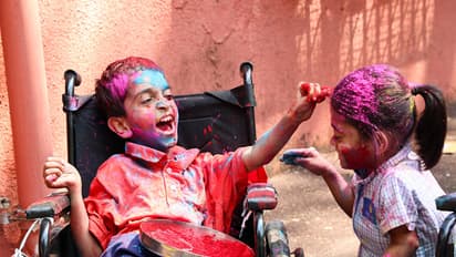 A specially abled boy applies colour to a girl as they celebrate ahead of the Holi festival