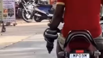 പാമ്പിനെ കയ്യിൽ ചുറ്റിപ്പിടിച്ച് ബൈക്കോടിക്കുന്ന യുവാവ്; ഞെട്ടിക്കുന്ന വീഡിയോ, വിമർശനം