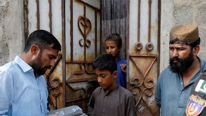 A worker from the National Database and Registration Authority (NADRA), speaks to Afghan citizens while verifying their identity cards on an online tab, during a door-to-door search and verification drive for undocumented Afghan nationals, in an Afghan Camp on the outskirts of Karachi (File Image/Reuters)