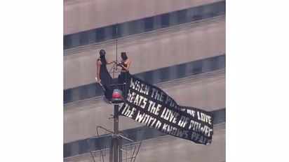 Two people scale to the top of Empire State Building carrying banner (Photo/Instagram/@angela_nikolau)