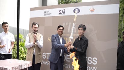FIDE Interim President Viswanathan Anand hands over the ceremonial Olympiad torch to Uzbek GM Javokhir Sindarov. (Photo: AICF)