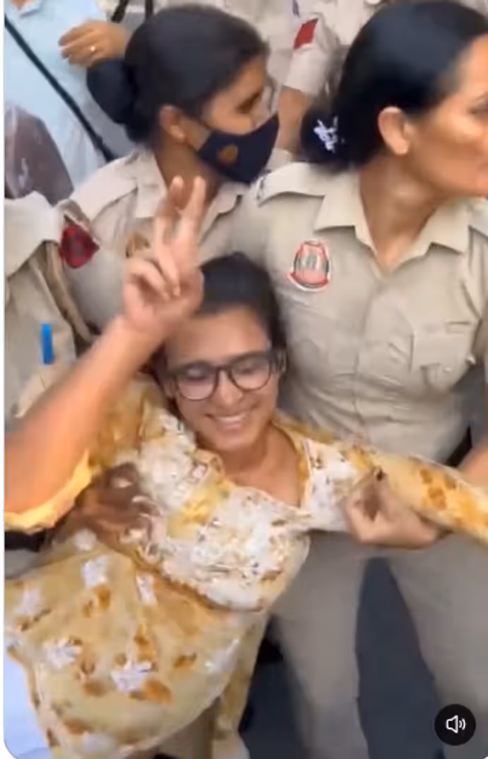 दिल्ली पुलिस के नेहा बोरा को घसीटते ले जाने की 5 तस्वीरें, चेहरे पर मुस्कान बरकरार