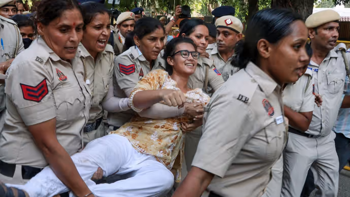 दिल्ली पुलिस के नेहा बोरा को घसीटते ले जाने की 5 तस्वीरें, चेहरे पर मुस्कान बरकरार